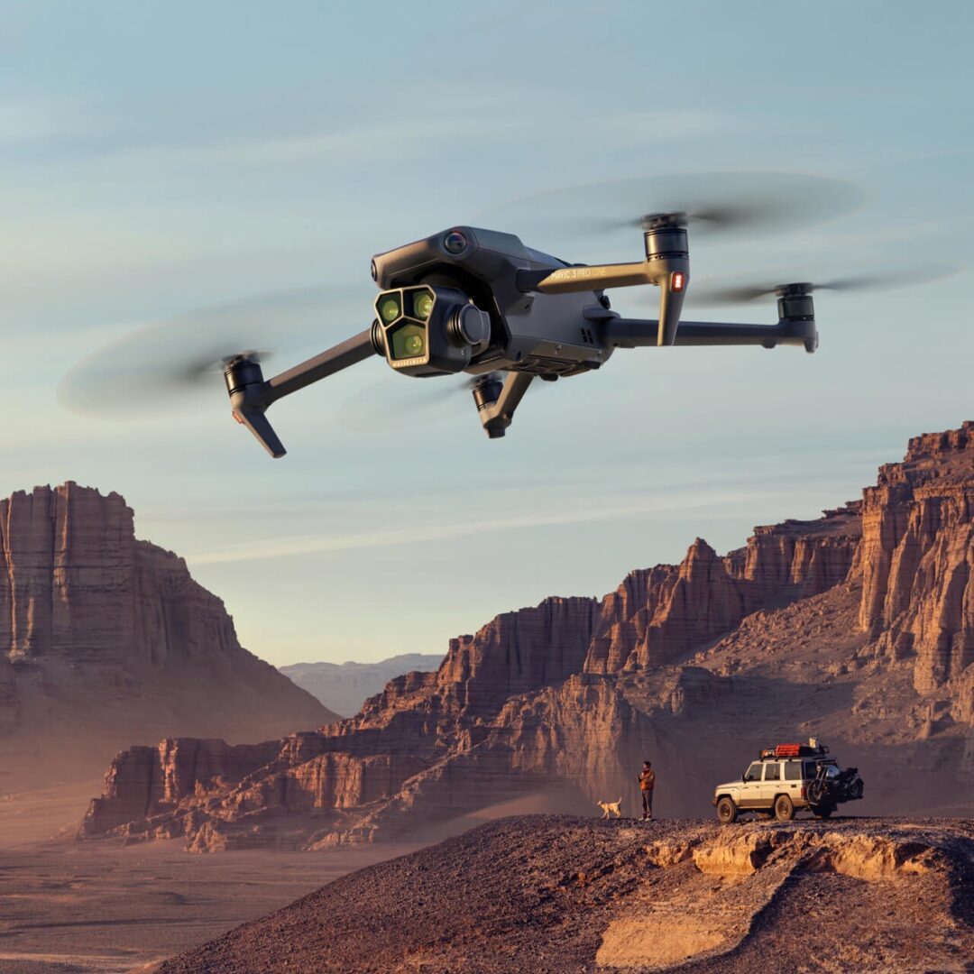 A helicopter flying over some mountains with a jeep in the background.