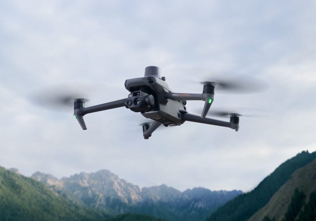 A black and silver drone flying over some mountains